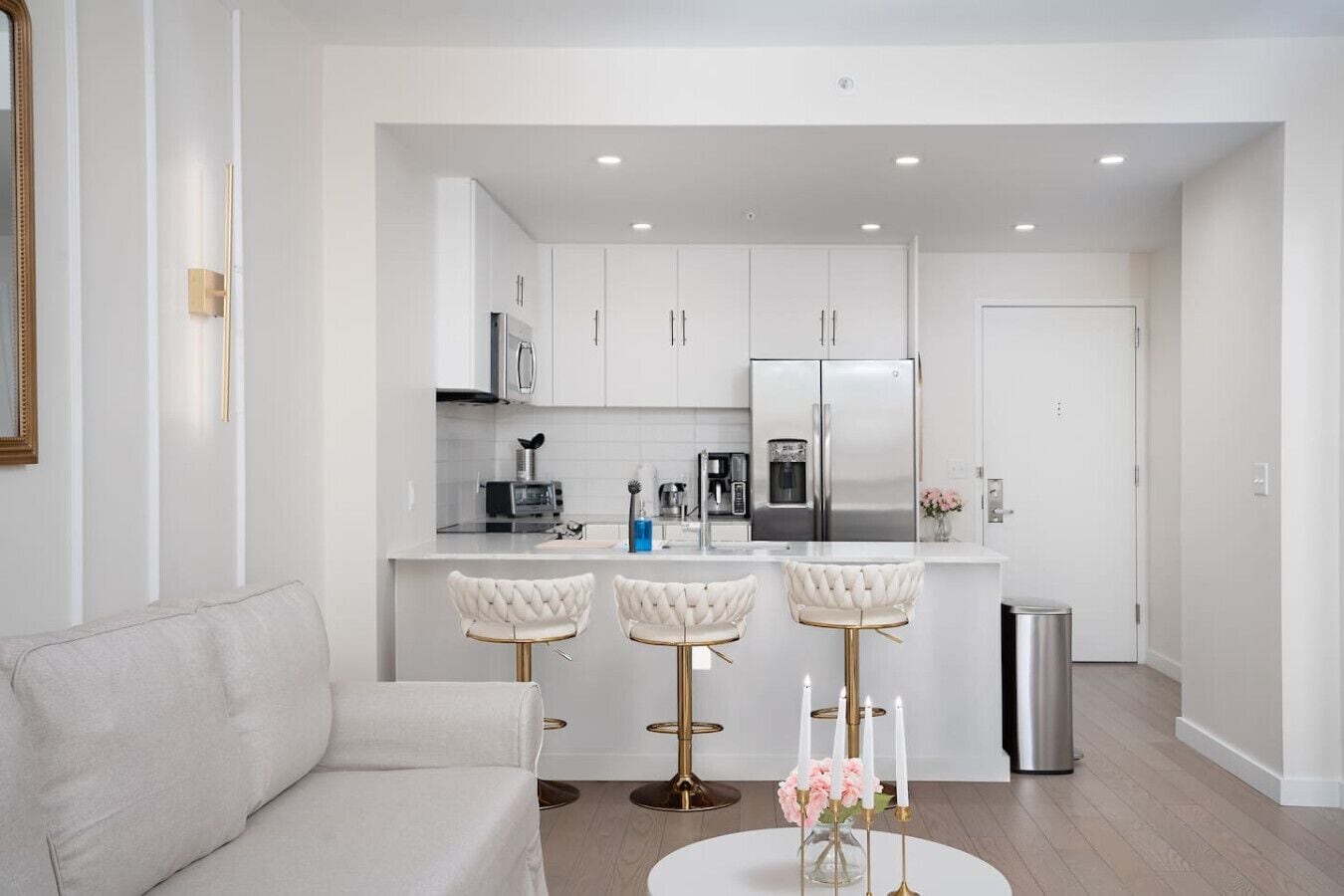 A modern kitchen with white cabinets, stainless steel appliances, and a central island with bar stools.