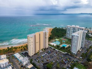 A high-rise hotel with multiple floors, a parking lot, and a view of the ocean and beach. - Playa Azul Beach Paradise (Luquillo)