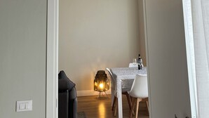 A room with a dining area, a sofa, and an air conditioning unit.