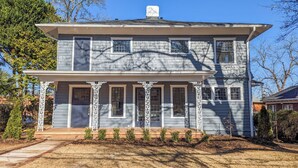 A two-story house with a symmetrical facade, featuring a central entrance flanked by columns, and a number "107" on the front door. - 1 bedroom apt, Steps from Swamp Rabbit Trail, 15 minute walk to Main st. (Greenville)