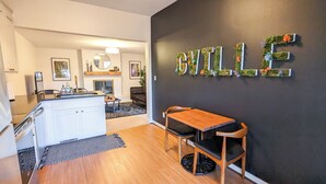 A modern kitchen with white cabinets, a wooden dining table, and a black wall with a 'BILLE' sign. - 1 bedroom apt, Steps from Swamp Rabbit Trail, 15 minute walk to Main st. (Greenville)