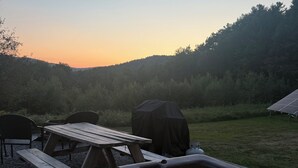 Ein Whirlpool mit Tisch und Stühlen, umgeben von einer Rasenfläche und Bäumen.