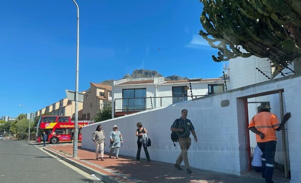 A street scene with pedestrians, a red bus, and buildings.