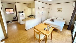 A compact hotel room with a single bed, a small table with a chair, a kitchenette, and a bathroom. - Cozy Apt. In The Heart of Beppu.『Nemuri no yu』202 (Beppu)