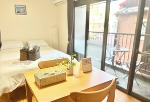 A hotel room with a bed, a wooden table with a basket and a vase, and a calendar.
