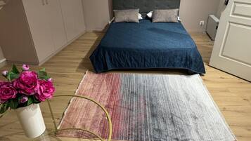 A bedroom with a bed, a bedside table, a chair, a wardrobe, and a potted plant.