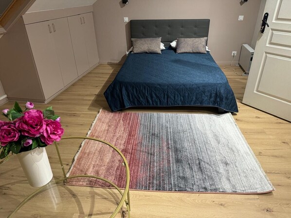 Un dormitorio con cama, mesita de noche, silla, armario y planta en maceta.