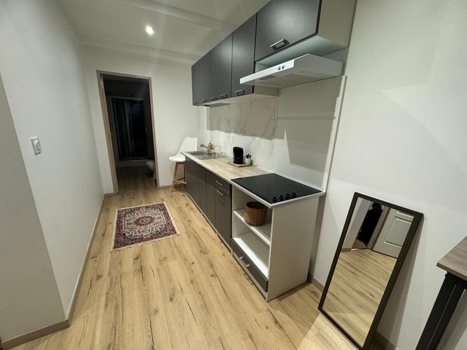 A compact kitchen with a built-in stove, dark cabinets, and a white countertop.