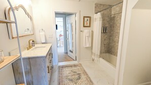 Une salle de bain avec un lavabo en marbre, une cabine de douche en verre et un tapis à motifs.