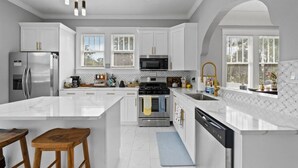 Una cocina moderna con armarios blancos, electrodomésticos de acero inoxidable y una isla grande.