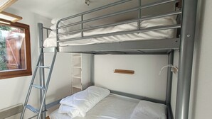 Ein Stockbett mit einer Leiter, einem Regal und einem Fenster.