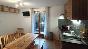 Eine kleine Küche mit Holzschränken, einem Esstisch und einem Spülbecken.