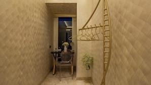 A narrow hallway with a wall-mounted drying rack and a chair with a vase of flowers. - A Residence - A Member of The Luxury Stay Group (Kota Kinabalu)