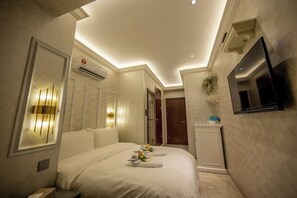 A hotel room with a bed, a TV mounted on the wall, an air conditioning unit, and a mirror. - A Residence - A Member of The Luxury Stay Group (Kota Kinabalu)