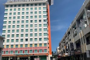 A multi-story hotel with a prominent vertical orange stripe, large windows, and a clear sky. - A Residence - A Member of The Luxury Stay Group (Kota Kinabalu)