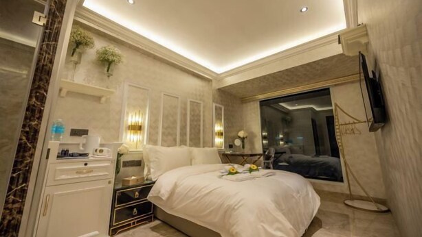 A modern bedroom with a large bed, bedside tables, a wardrobe, and a TV mounted on the wall. - A Residence - A Member of The Luxury Stay Group (Kota Kinabalu)