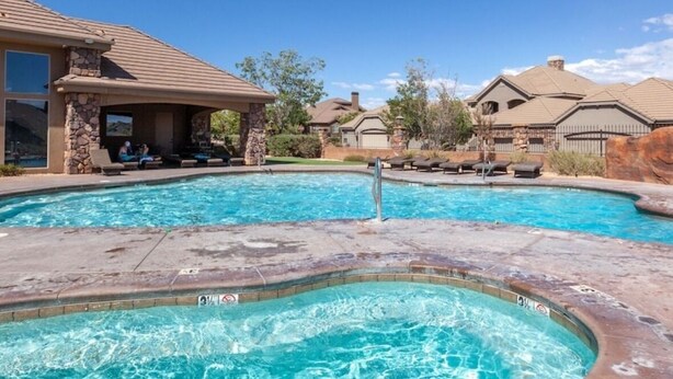 A swimming pool with a hot tub, lounge chairs, and a covered seating area.