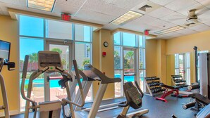 A gym with cardio equipment, weight machines, and a view of a pool through large windows. - Life is Better at the Beach!  Charming 3 bedroom, 3 bath condo at Ariel Dunes 1 (Miramar Beach)