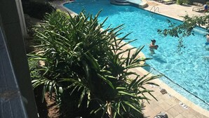 A swimming pool with a curved edge, surrounded by lounge chairs and a small fountain. - Pool View 2 Bedroom/2 Bath Condo in Houston's Medical Center (Houston)