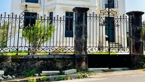 Un bâtiment à deux étages, doté d’une façade blanche, de nombreuses fenêtres et d’une clôture en fer forgé noir.