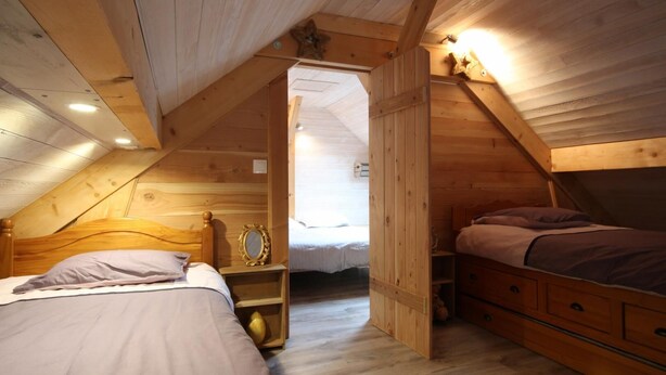 A cozy attic bedroom with two beds, wooden walls, and a sloped ceiling. - Chalet du Menhir - SAINT-MICAUD (SAINT-MICAUD)