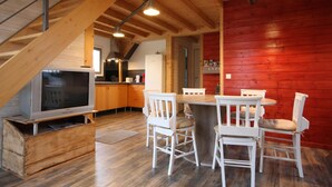 A modern kitchen with a dining area, wooden beams, and a red accent wall. - Chalet du Menhir - SAINT-MICAUD (SAINT-MICAUD)