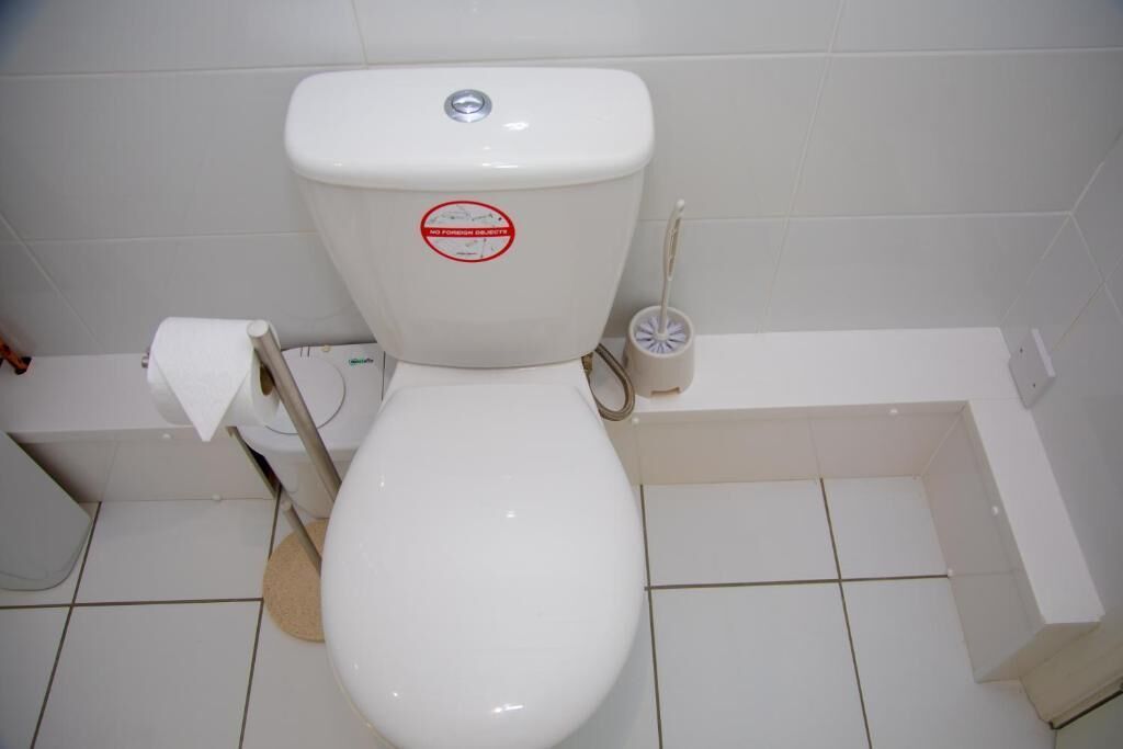 Un waterino bianco con un adesivo rosso, un portasciugamani e un getto per bidet.