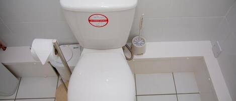 Un waterino bianco con un adesivo rosso, un portasciugamani e un getto per bidet.