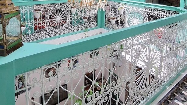A room with teal-colored walls, white decorative railings, and a patterned floor. - Riad Nostalgie (Tetouan)