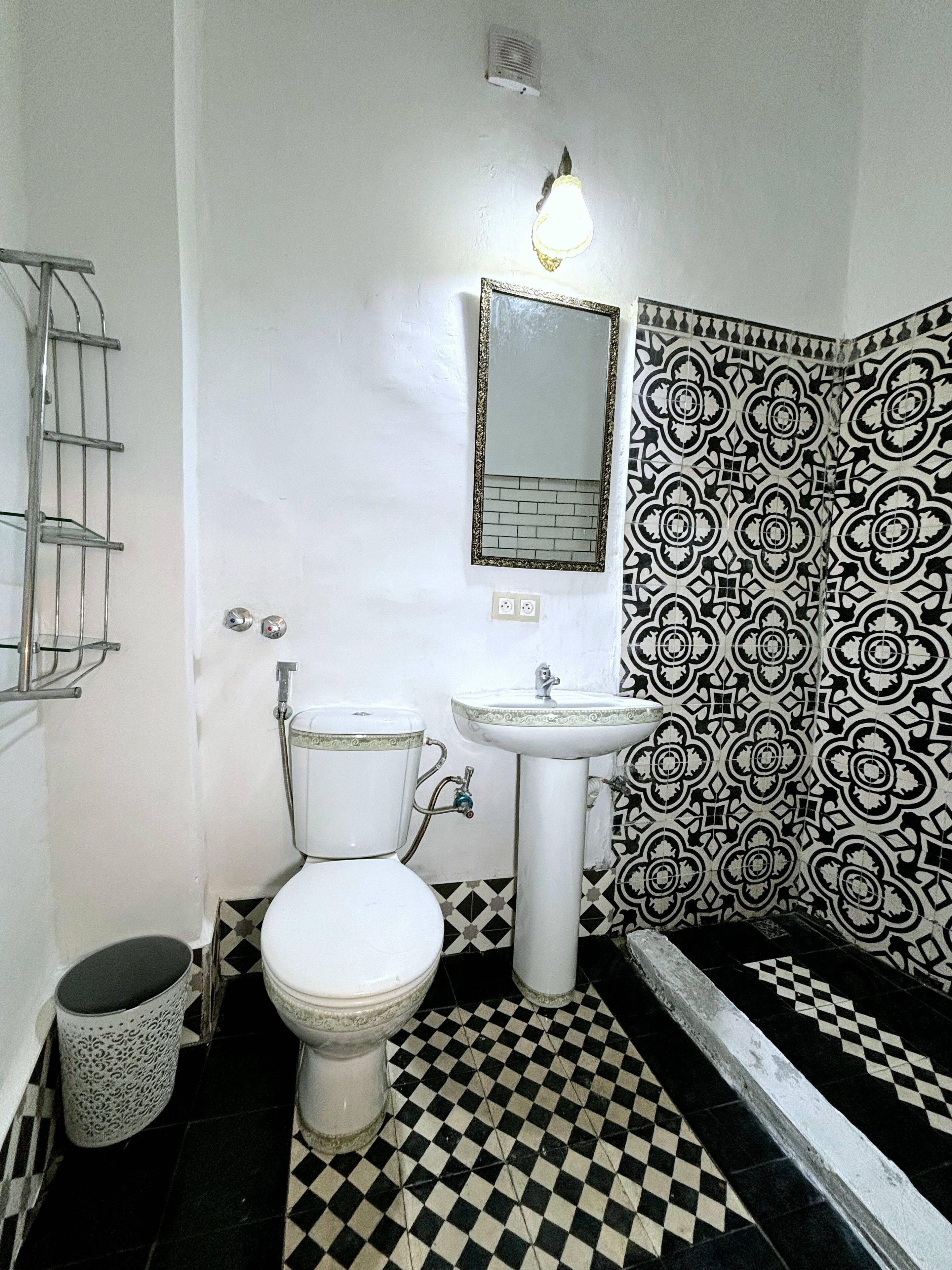 Un baño con inodoro, lavamanos y azulejos estampados.