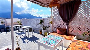 A rooftop terrace with a table, chairs, and potted plants. - Riad Nostalgie (Tetouan)