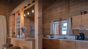A wooden interior with a bar area, stools, a sink, and a window with curtains. - Chalet San Marco - mountain luxury stay for 6 - OVO Network (La Clusaz)