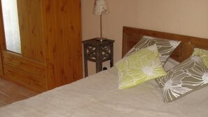 Una cama con edredón blanco, cabecera de madera y almohadas estampadas.