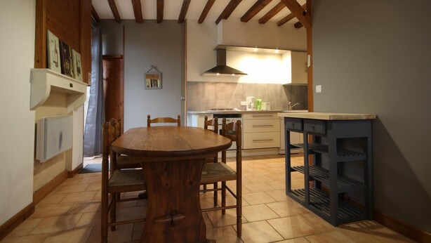 Un comedor con una mesa y sillas de madera, una cocina al fondo y un mueble empotrado.