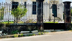 Un edificio a due piani con facciata bianca, diverse finestre e una recinzione in metallo nero.