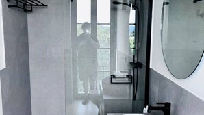 Un bagno moderno con doccia vetro, uno specchio grande e un lavandino bianco.