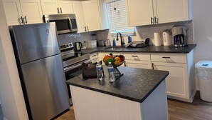 A modern kitchen with white cabinets, stainless steel appliances, and a black countertop.