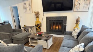 A modern living room with grey sofas, a coffee table, and a fireplace.