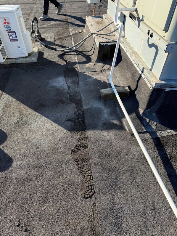 Une surface en béton avec une ligne blanche servant de marquage, un appareil de la marque Mitsubishi Sum et un tuyau raccordé à une machine.