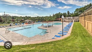A swimming pool area with multiple pools, lounge chairs, and a covered pavilion.