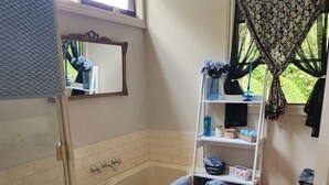 Un baño con bañera, ducha, lavabo y ventana con cortina.