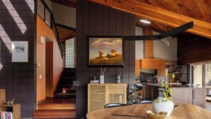 A modern kitchen with wooden cabinets, a dining table with a vase, and a staircase leading to another level. - Architects Dream Home | Secluded Retreat | 30 Day (Golden)