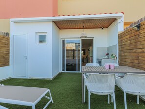 A small patio area with a table and chairs, a door, and a wooden fence.