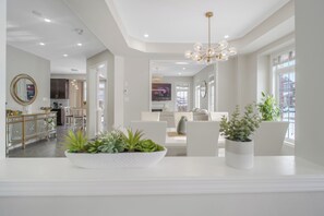 A modern living room with a white sofa, a coffee table with plants, and a chandelier. - 4-bedroom house in charming Haydon with fitness room, WiFi, AC (Haydon)