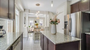 A modern kitchen with stainless steel appliances, a granite countertop, and a dining area with a vase of flowers.