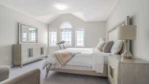 A bedroom with a bed, dresser, mirror, and a window with a view.