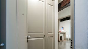Un couloir avec des portes blanches et une cheminée au fond.