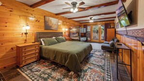 A log cabin-style bedroom with a bed, dresser, and a ceiling fan. - Views, Hot tub, Pool Table! (Sevierville)