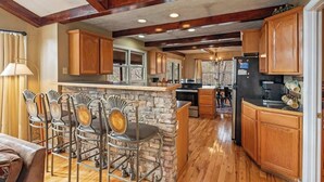 A kitchen with wooden cabinets, a stone island, and bar stools. - Views, Hot tub, Pool Table! (Sevierville)