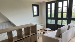 Un salon moderne avec un canapé, une petite table ronde et une bibliothèque intégrée.